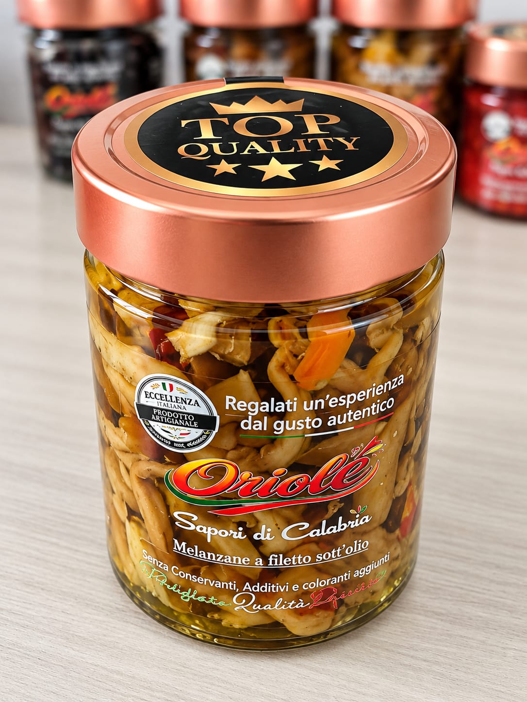 Close-up product photograph of a glass jar of lemon spread with a copper-colored lid, set on a tabletop with a softly blurred indoor background and diffuse daylight.